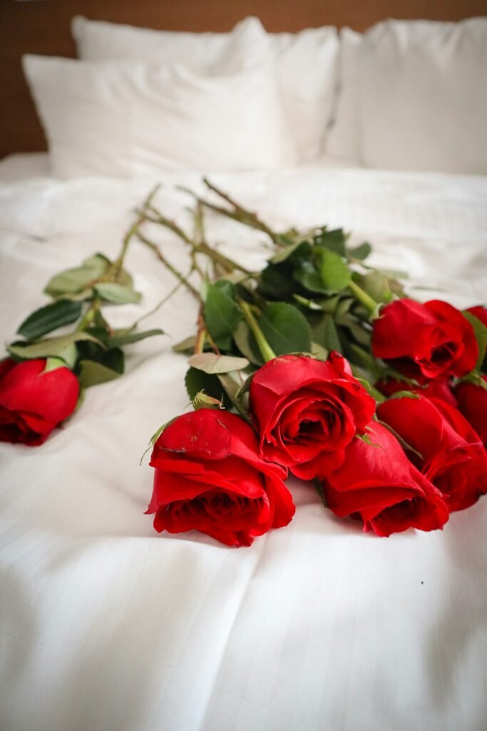 Red roses laid on a white bed for a romantic setup